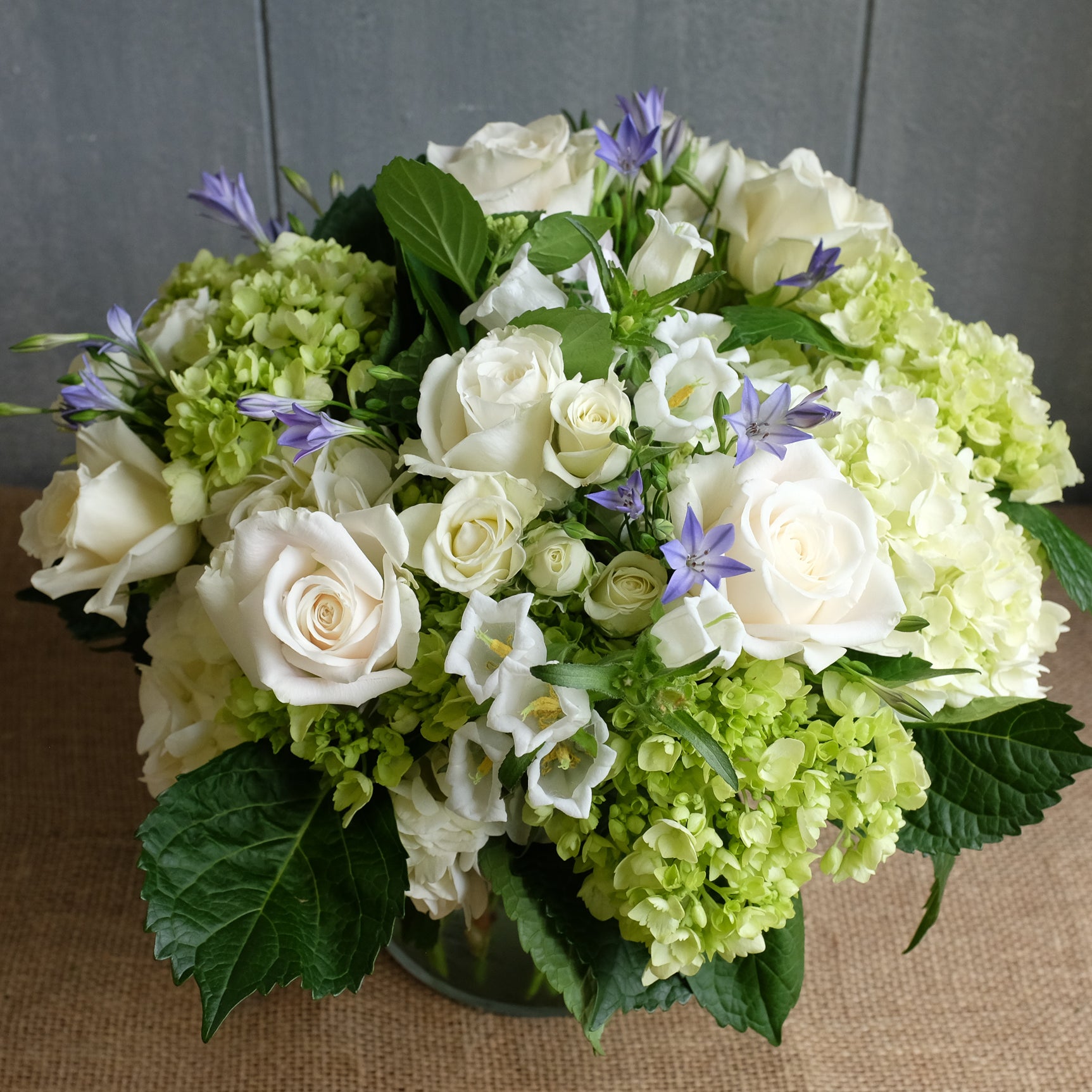 Lush floral bouquet of white and green flowers with a touch of blue