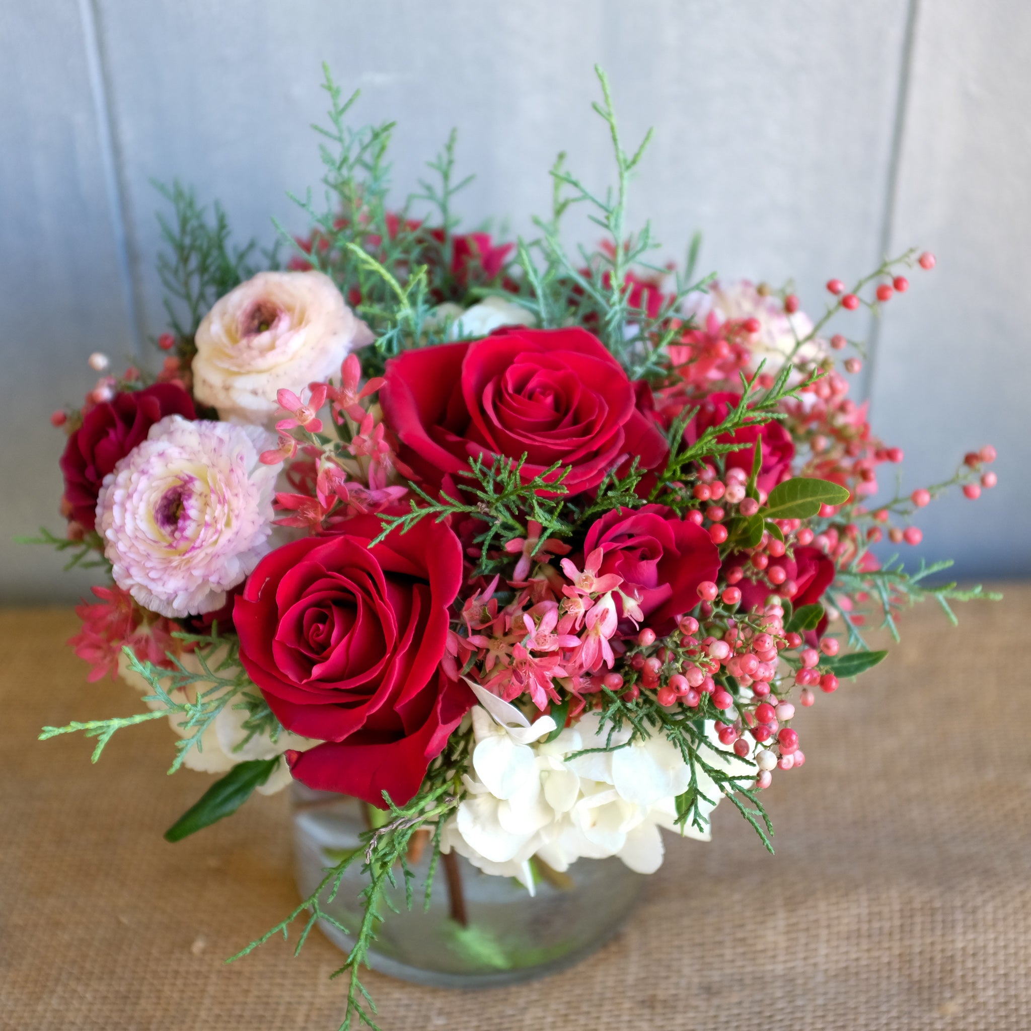 Flower arrangement with pepperberry and cappuccino ranunculus.