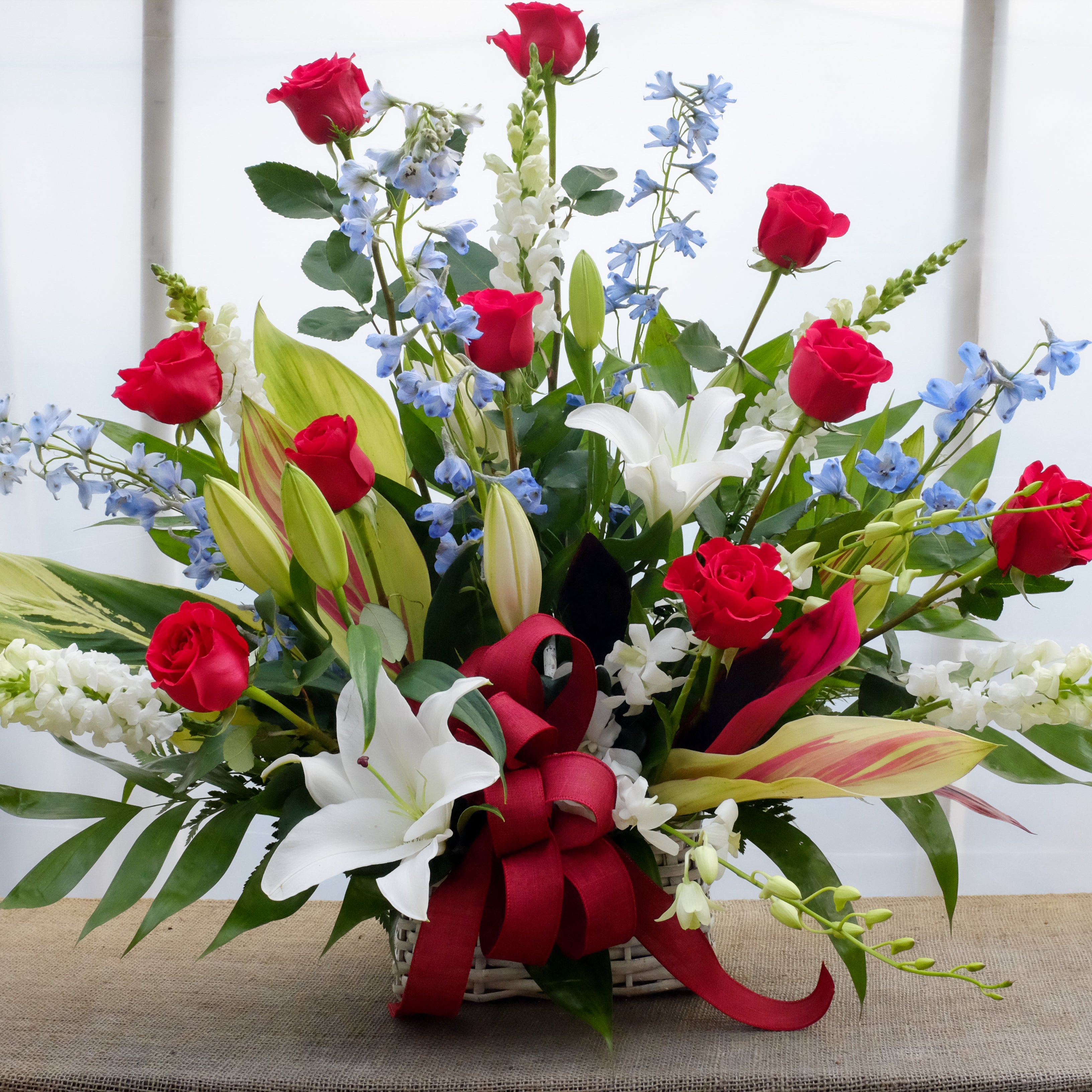 Denmark Funeral Basket: Red Roses, White Lilies, Delphinium and Snap Dragons. Designed by Michler's Florist in Lexington, KY