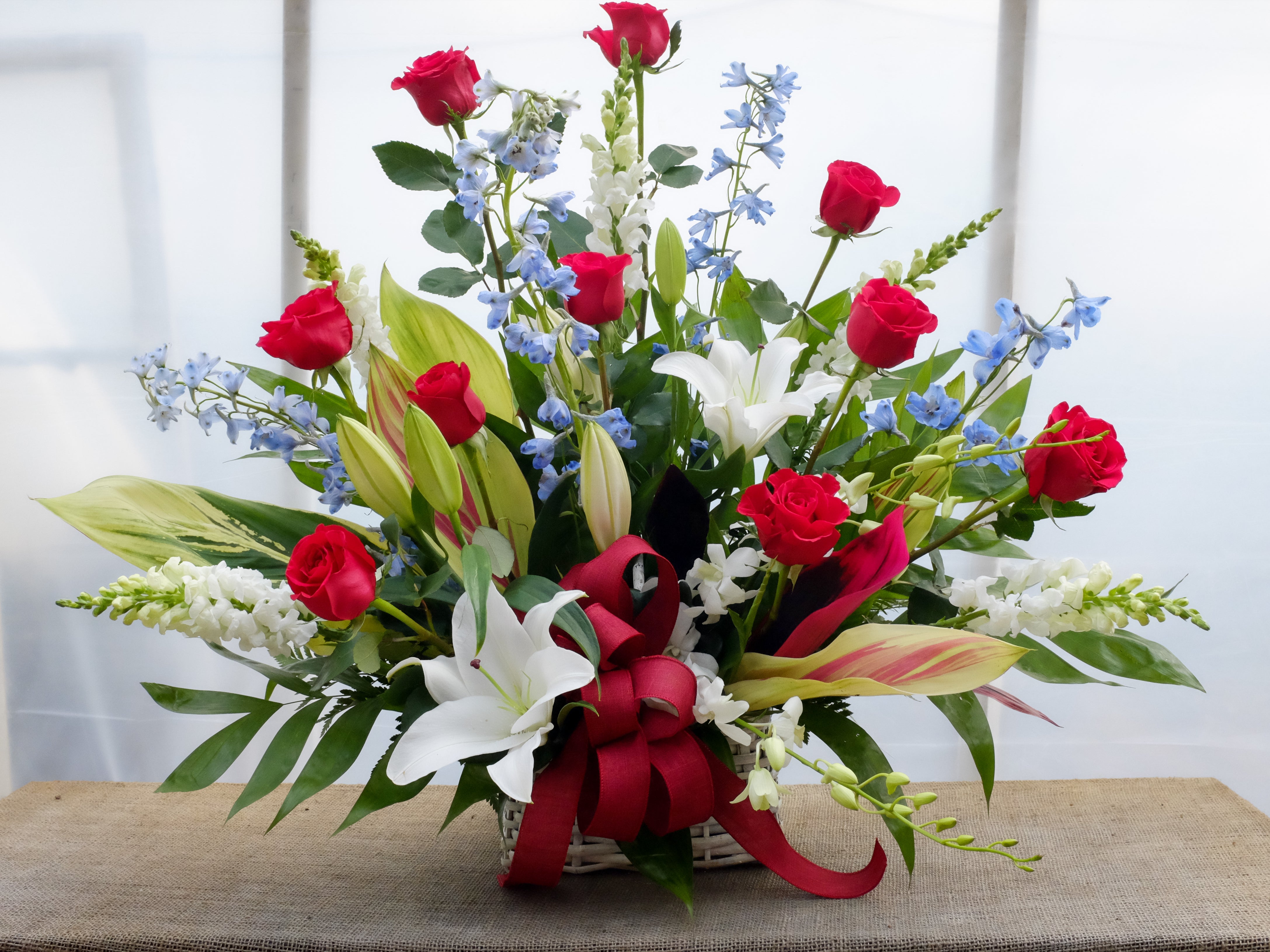Denmark Funeral Basket: Red Roses, White Lilies, Delphinium and Snap Dragons. Designed by Michler's Florist in Lexington, KY