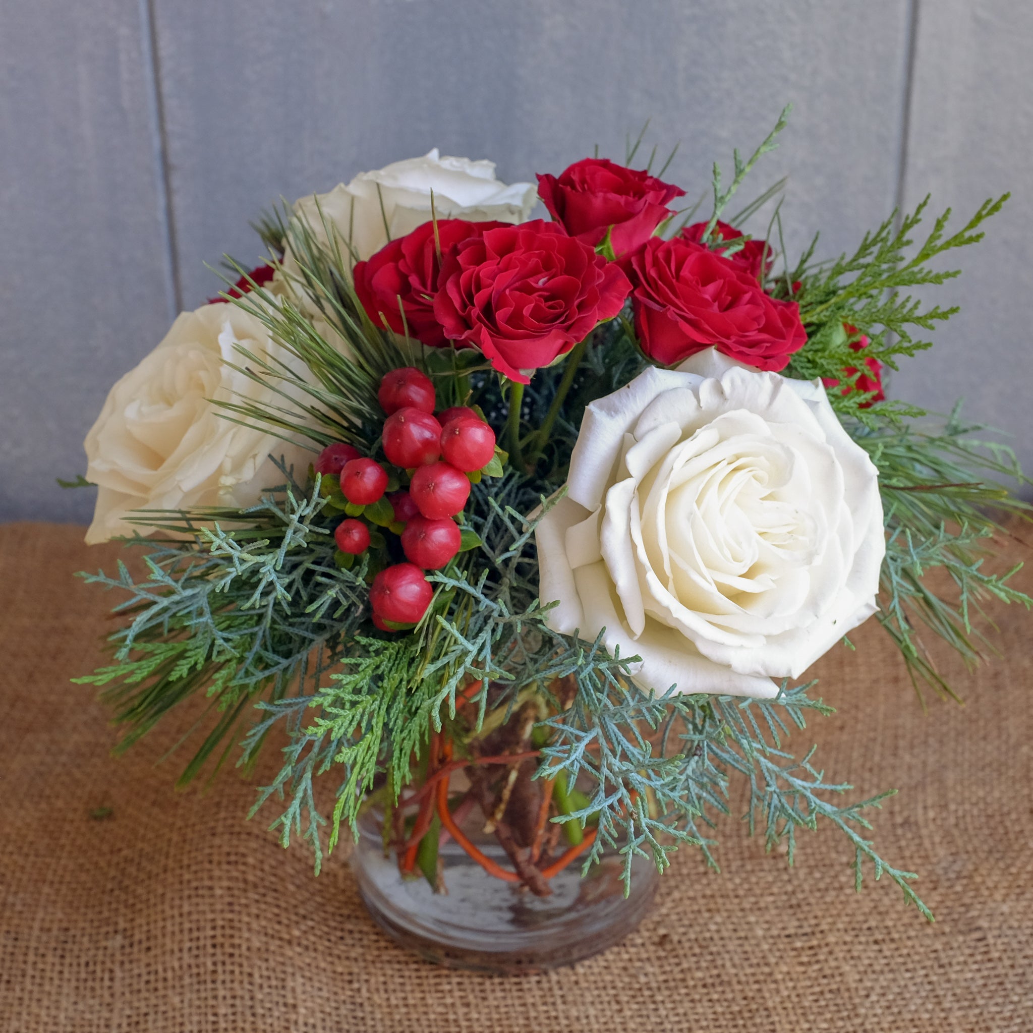 Vase of red and white flowers with christmas greens