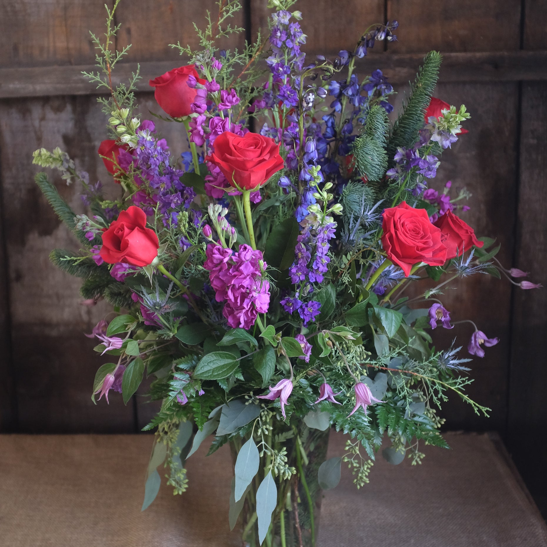 a tall and elegant floral design with roses, delphinium, and seeded eucalyptus by Michler's