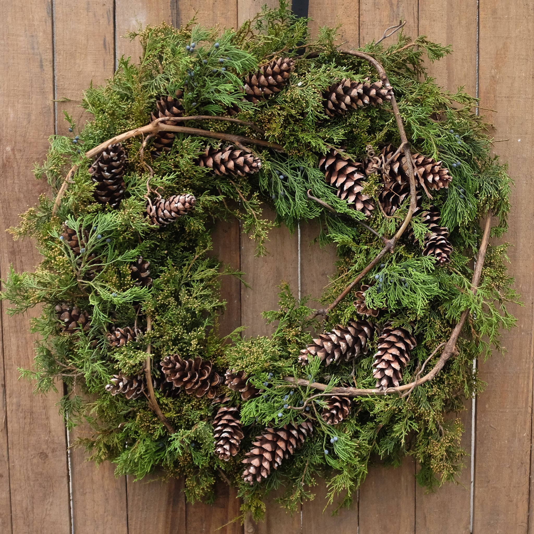 mixed evergreen wreath with pinecones and wooden accents by Michler's