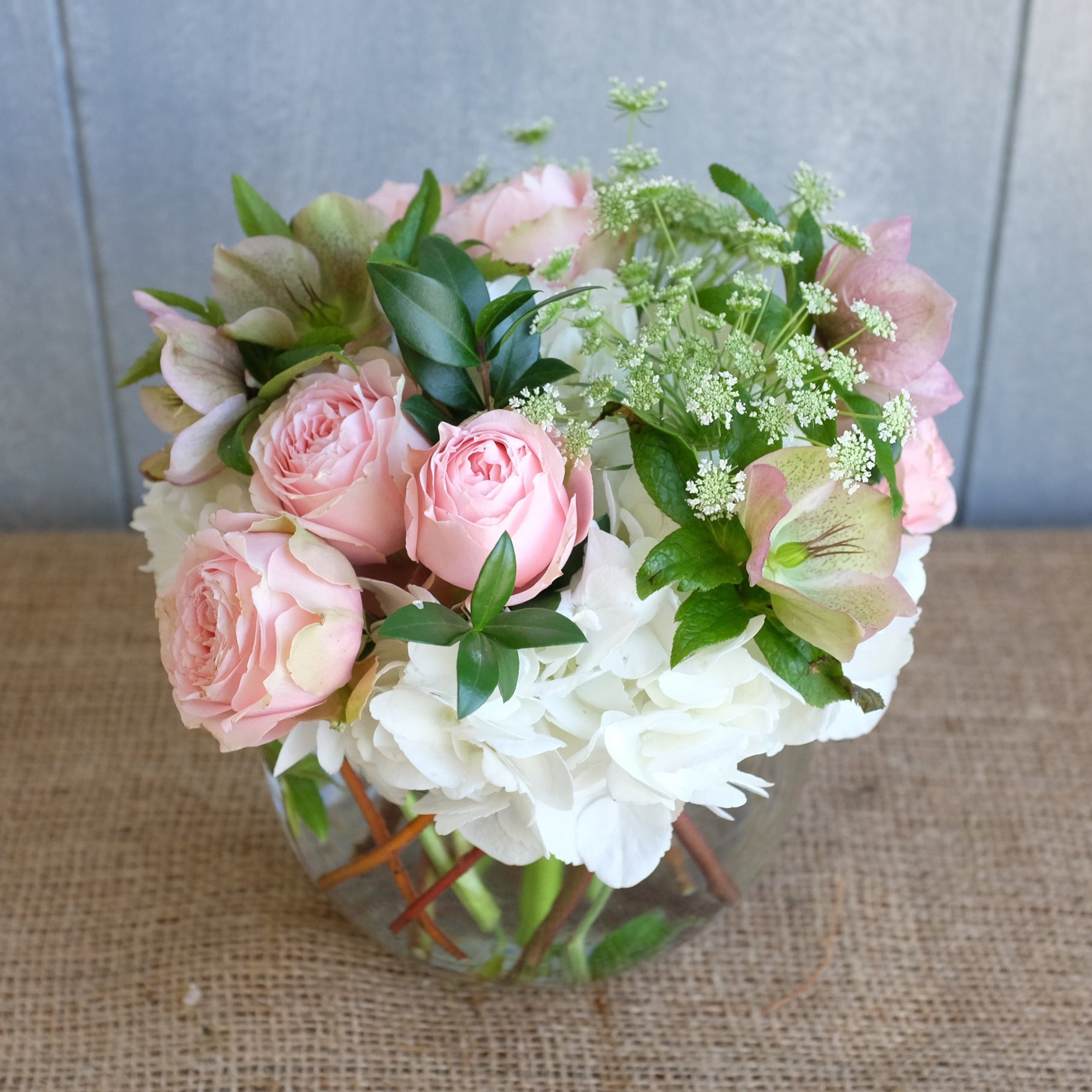 Bouquet of white hydrangea and pink roses with seasonal foliage.