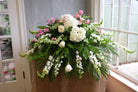 Casket spray in pink and white with snapdragons, roses, hydrangea and tulips.