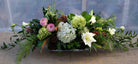 Floral centerpiece with lilies, freesia, ranunculus in a glass rectangular vase | Michler's Florist