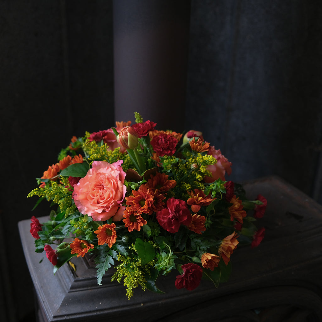 centerpiece with peach roses, red carnations, orange mums and tulips