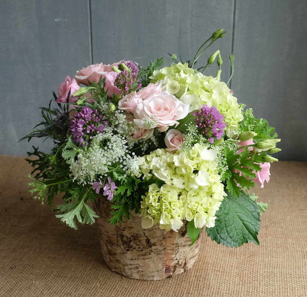 Flower bouquet with pink and green flowers in a birch bark vase