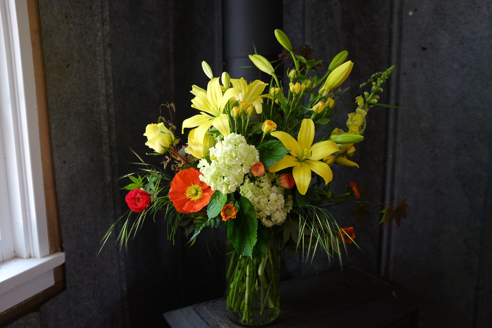 Flower design with orange poppies and yellow lilies by Michler's Florist