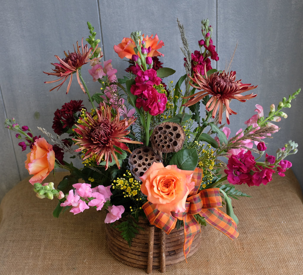 warm-toned flower basket with roses, mums, stock, and dried accents