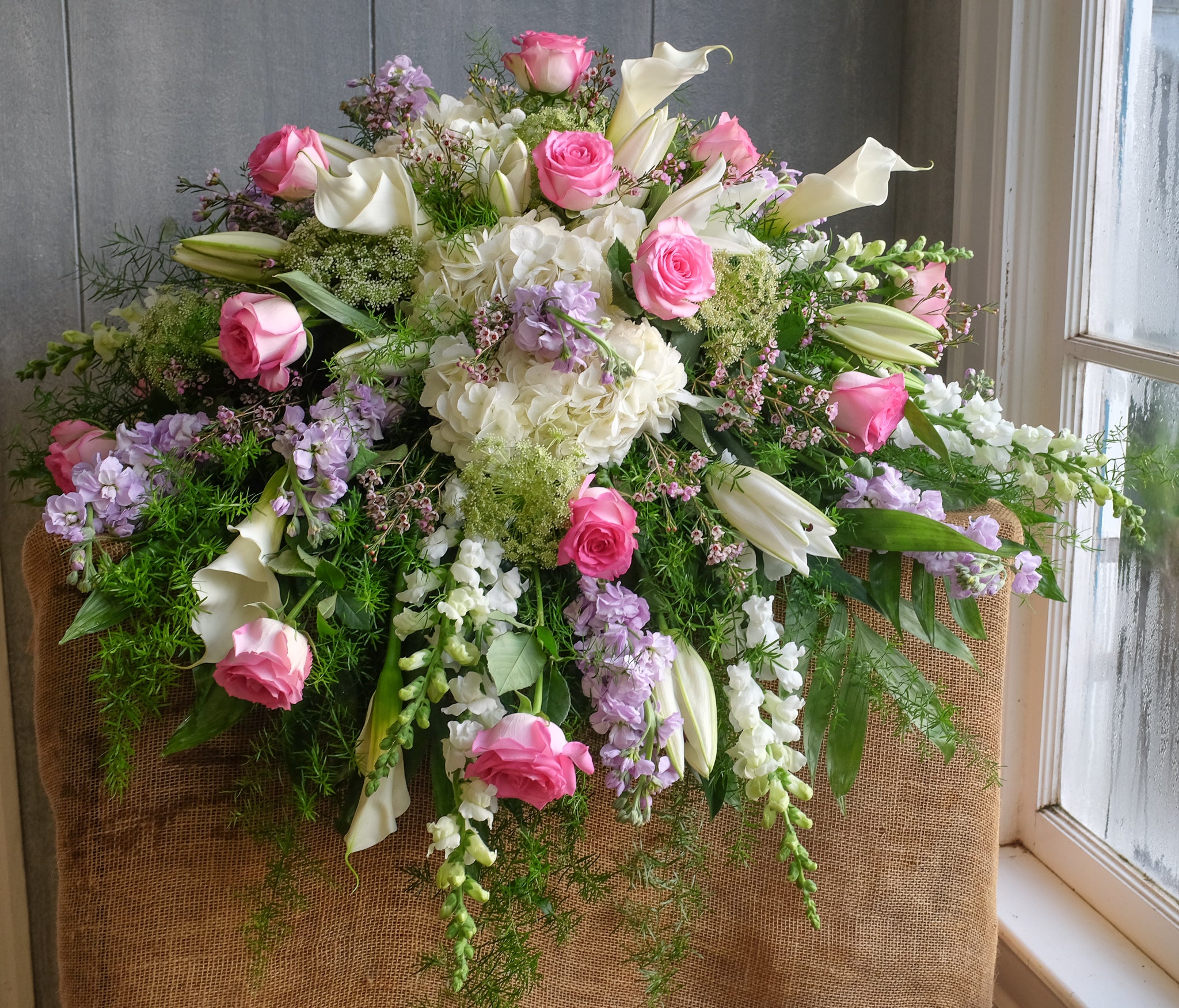 floral casket spray with roses, hydrangea, lilies, and stock by Michler's