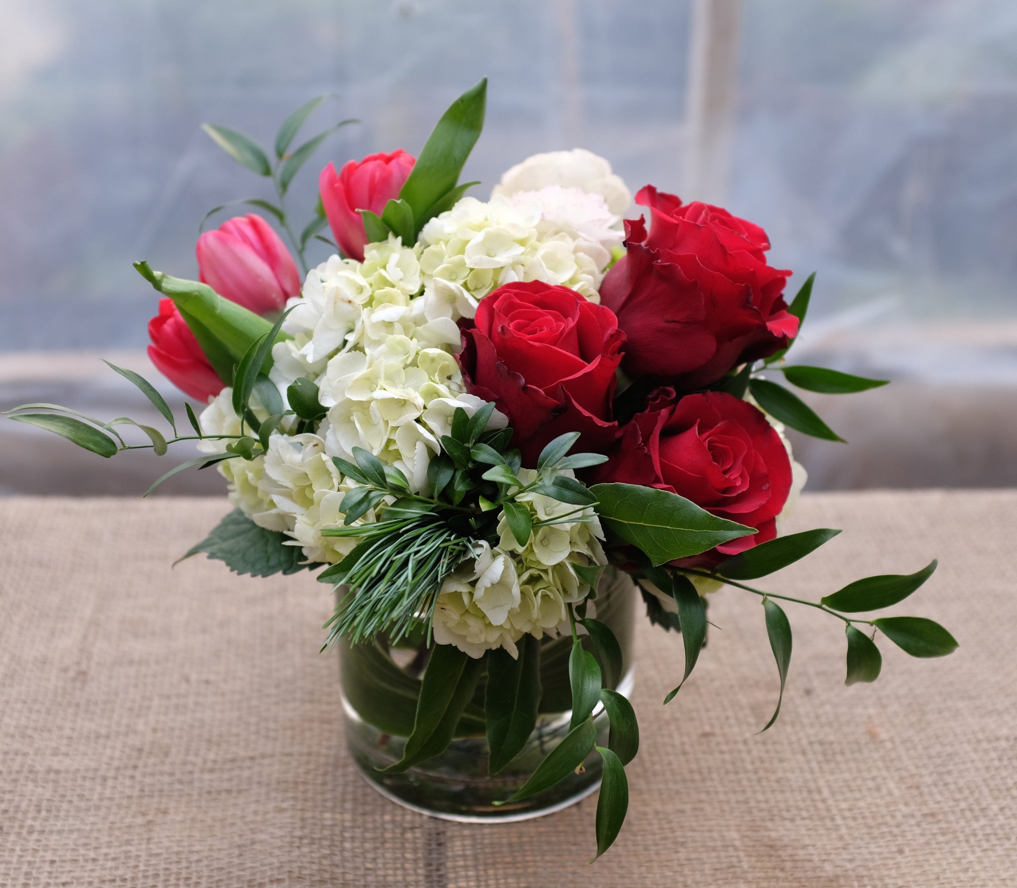 Blitzen: Christmas Flower Arrangement with Red Roses, Red Tulips, and White Hydrangea. Designed by Michler's Florist in Lexington, KY