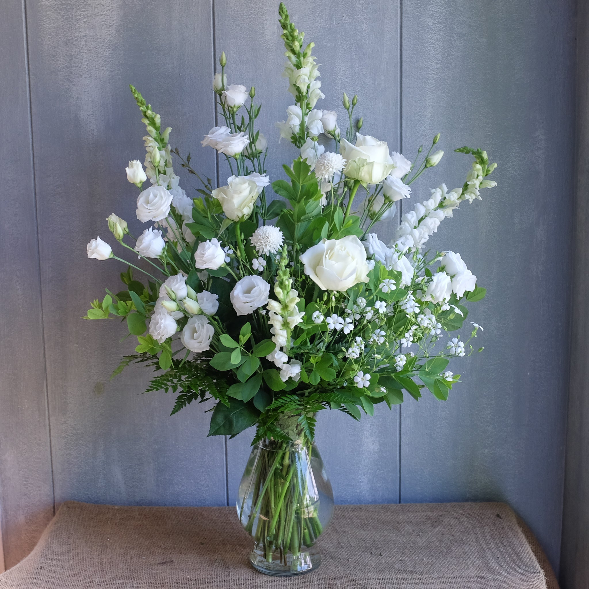 tall and elegant floral arrangement with white roses, ranunculus, and stock by Michler's
