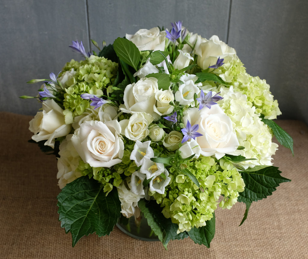 Lush floral bouquet of white and green flowers with a touch of blue
