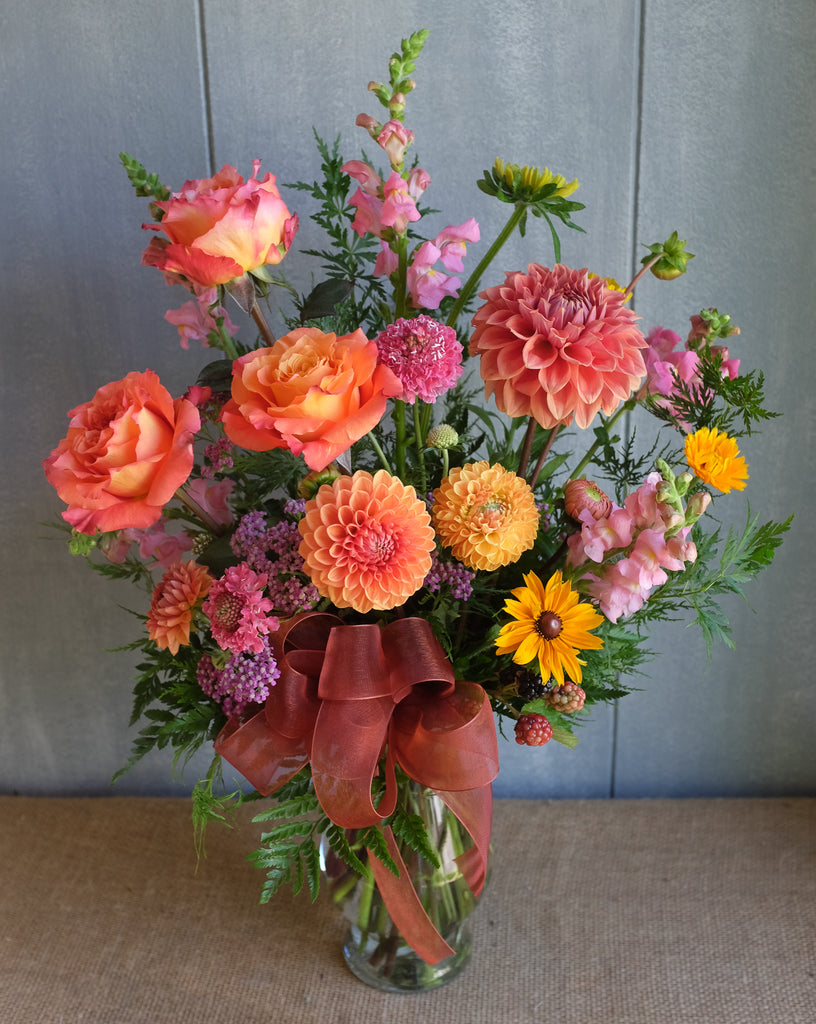Floral arrangement with peach dahlias, peach roses, black-eyed susan, sunflower by Michler's florist