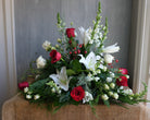 Red and White Christmas flowers with evergreens.  Large all around design by Michler's Florist with roses, snapdragons, berries, and cedar