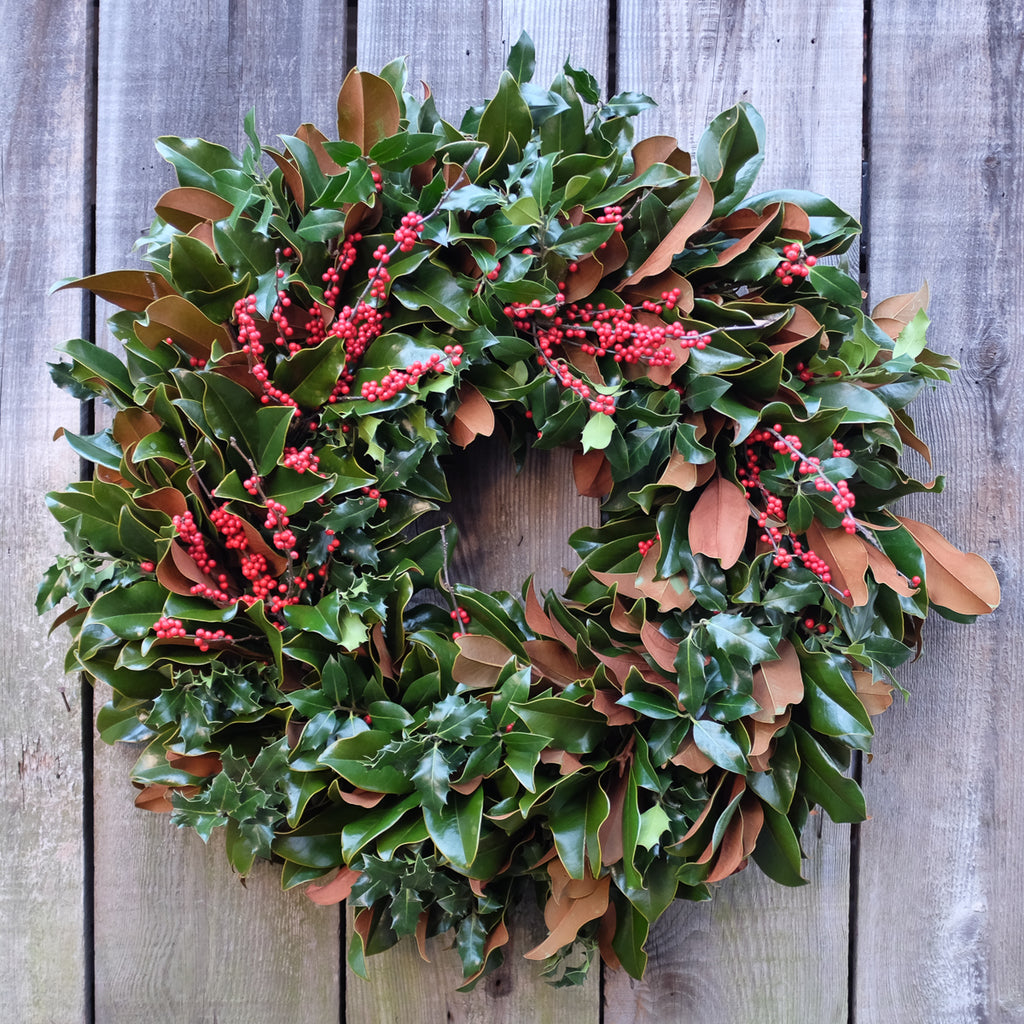Magnolia wreath with holly greens and berries designed by Michler's Florist