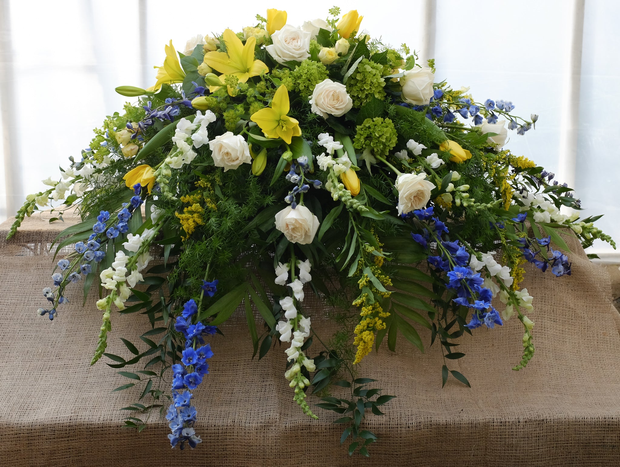 A casket spray with white roses, yellow lilies and golden rod from Michler's Florist