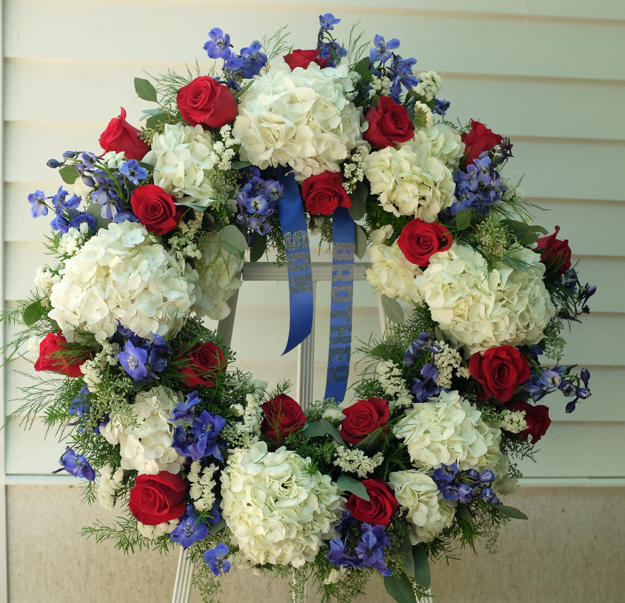 Floral Arrangment by Michler's Florist with white hydrangea, red roses, and blue delphinium
