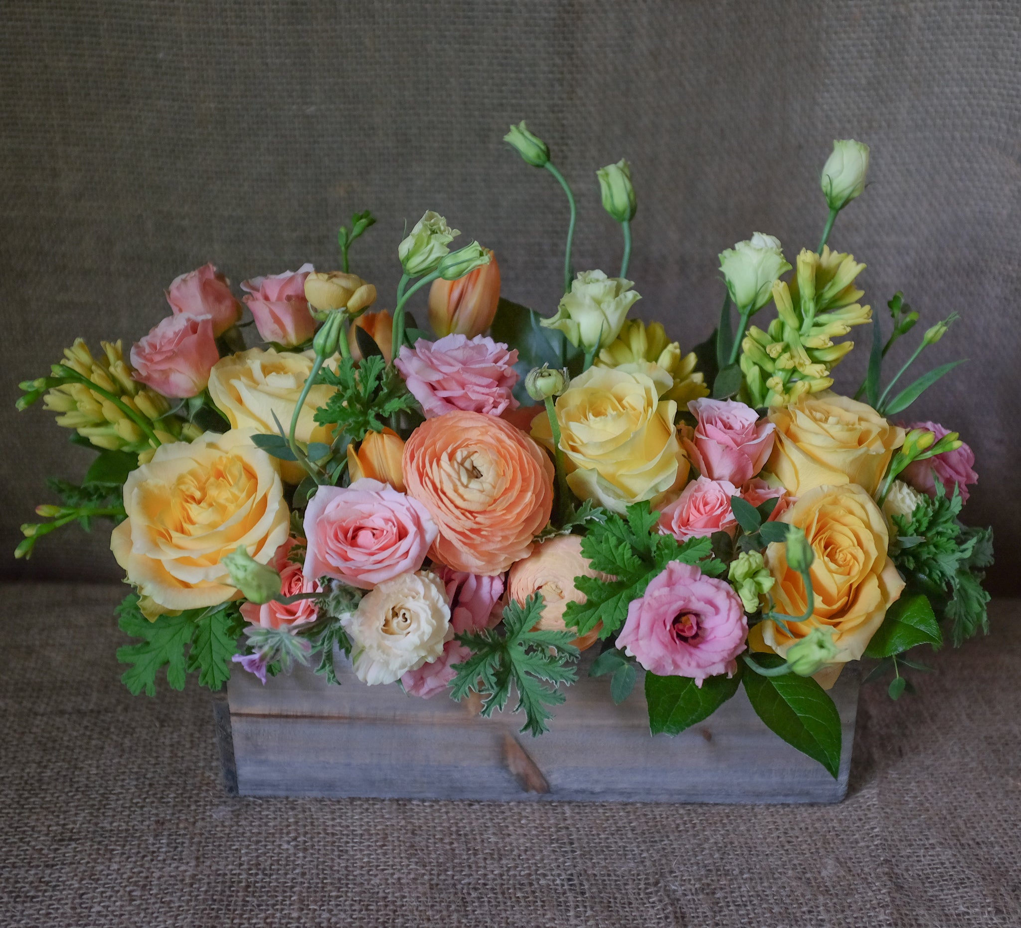 Pastel flowers arranged in a wooden box by Michlers Florist.