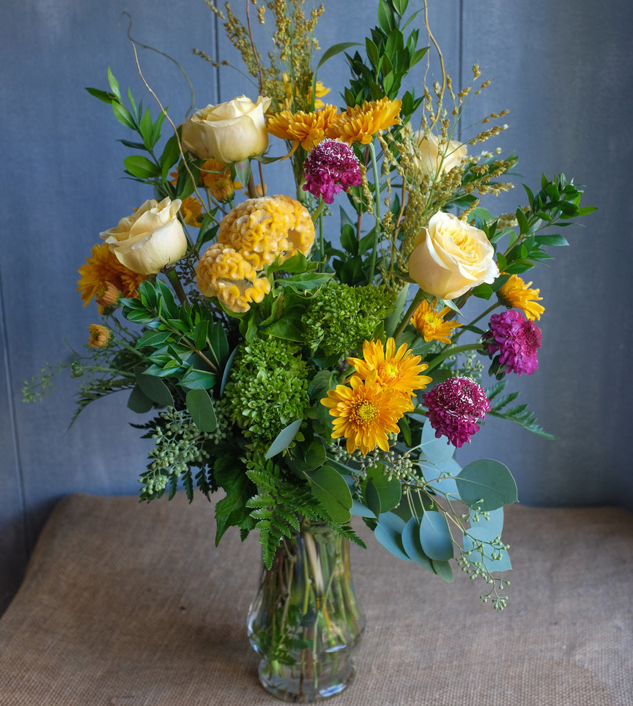 Tall bouquet featuring golden fall tone flowers.