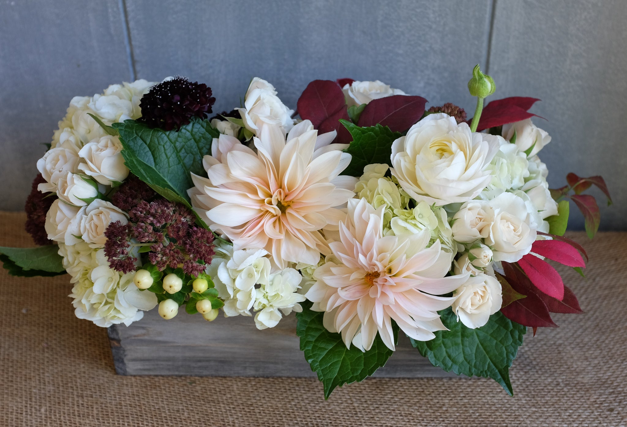 low and long flower arrangement with roses, hydrangea, mums, and scabiosa by Michler's