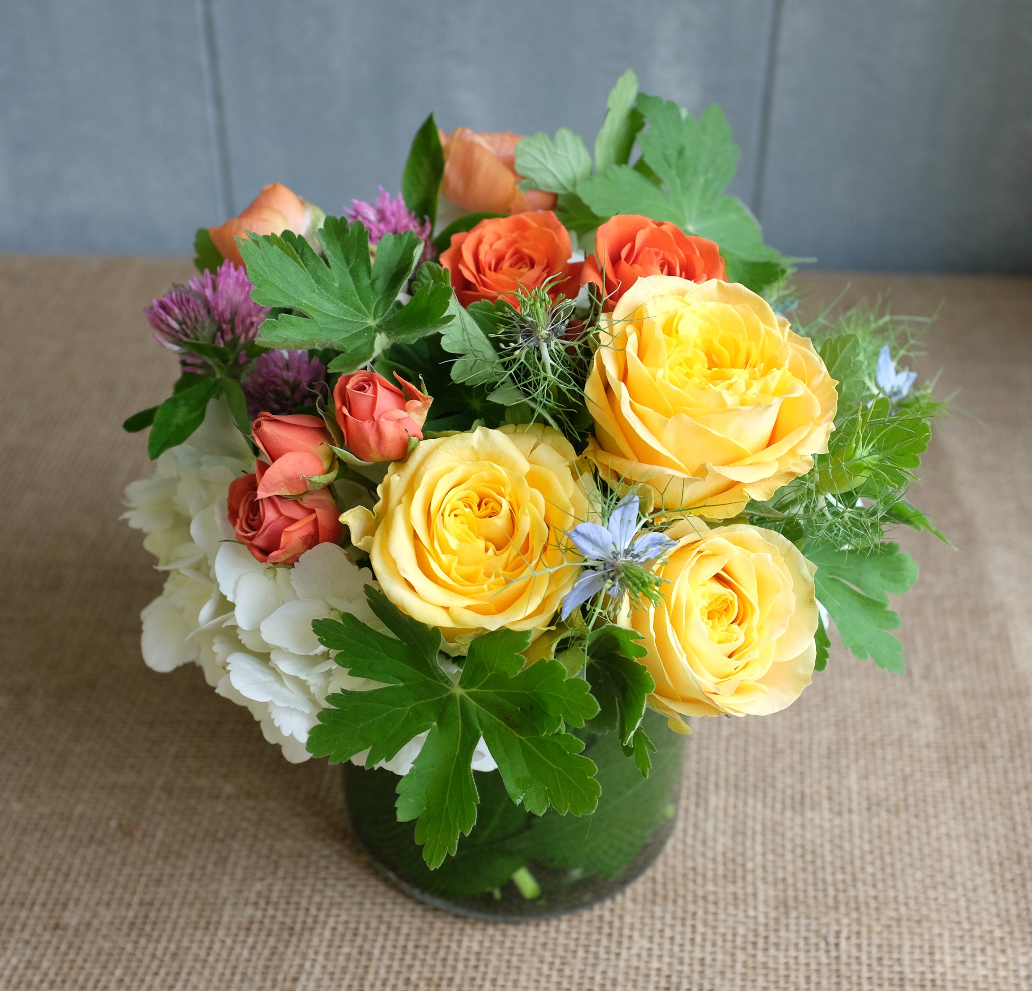 Lush bouquet of yellow and orange roses with white hydrangea and garden foliage