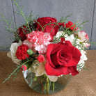 a holiday flower arrangement with roses, peppermint carnations, hydrangea, and wintergreens by Michler's