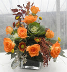 Floral arrangement with orange roses, ornamental cabbage, and eucalyptus 