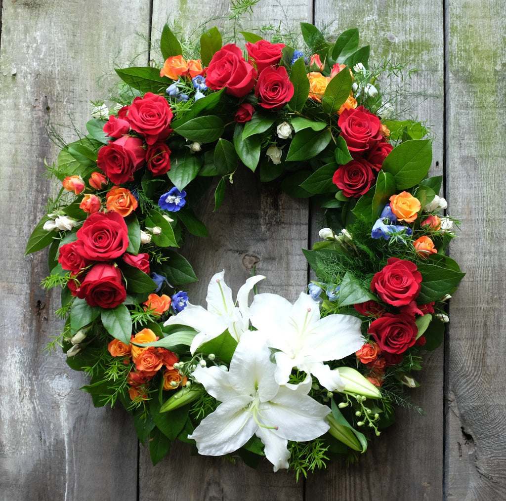 Luxembourg Sympathy Funeral Wreath with Red and Orange Roses, and White Lilies. Designed by Michler's Florist in Lexington, KY