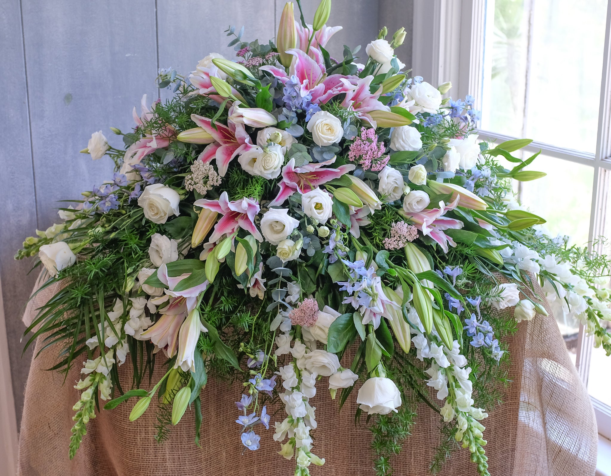 floral casket spray with roses, lisianthus, lilies, larkspur, and stock by Michler's Florist in Lexington, KY