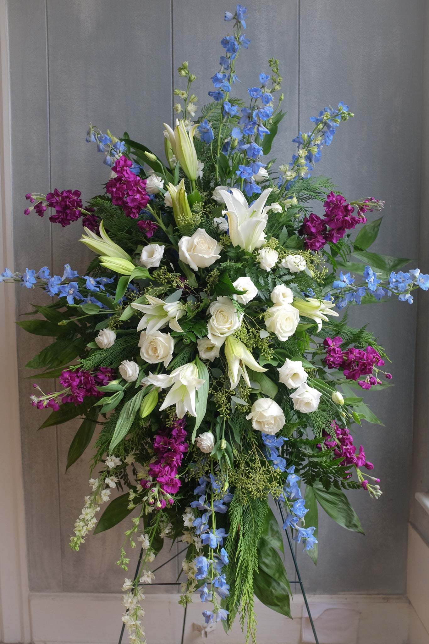 floral easel spray with lilies, roses, seeded eucalyptus, and stock by Michler's