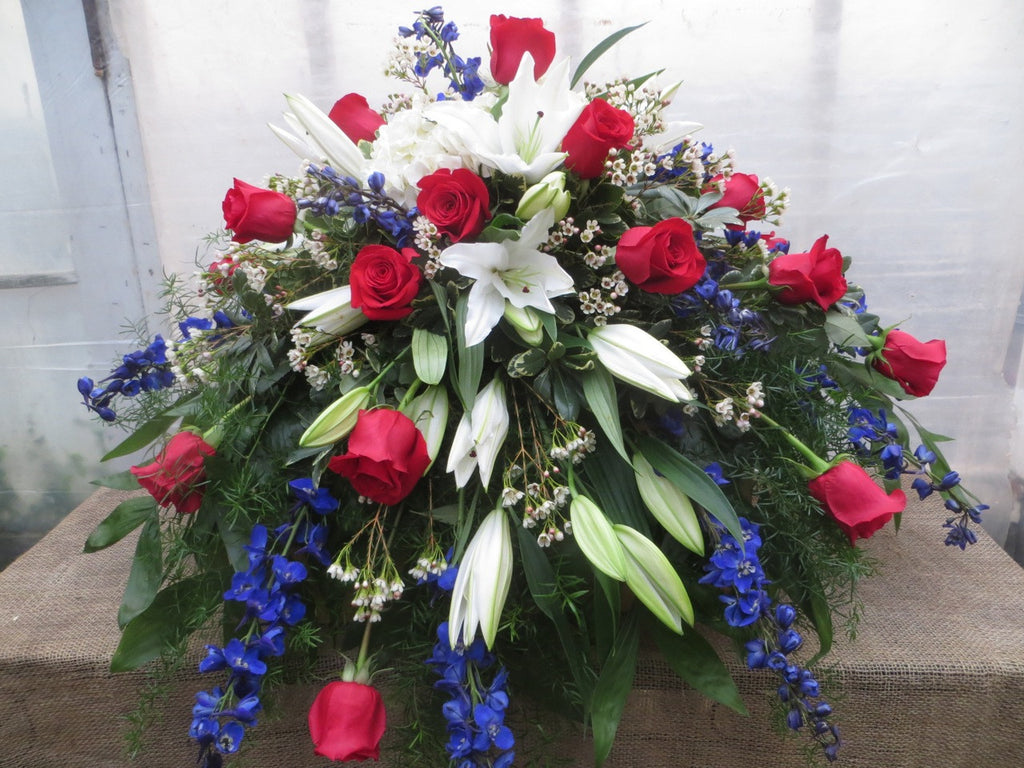 Patriotic Casket Spray with red roses, white lilies, and blue delphinium. Michler's Florist, Greenhouses & Garden Design
