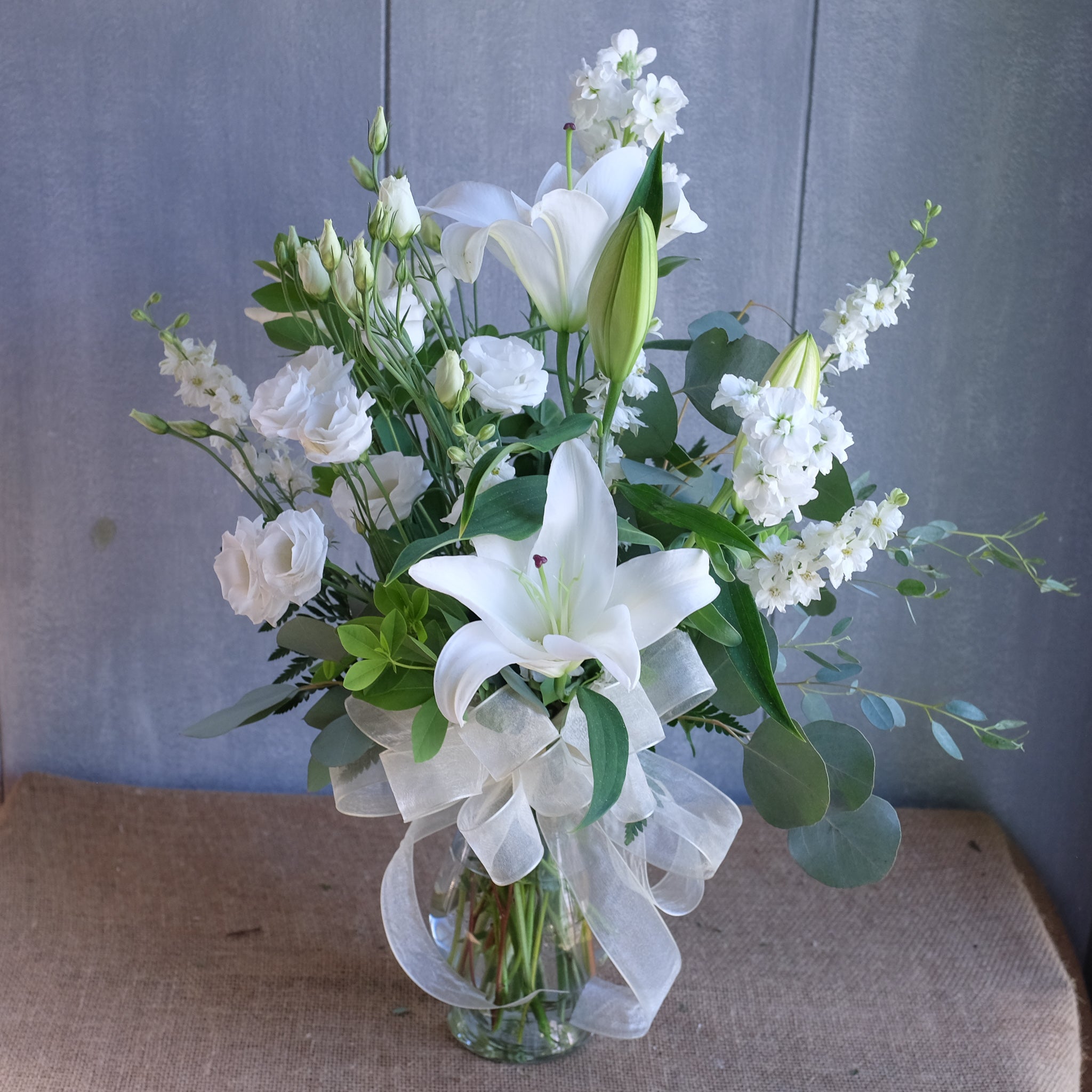 tall and elegant floral arrangement with lilies, ranunculus, and greenery by Michler's