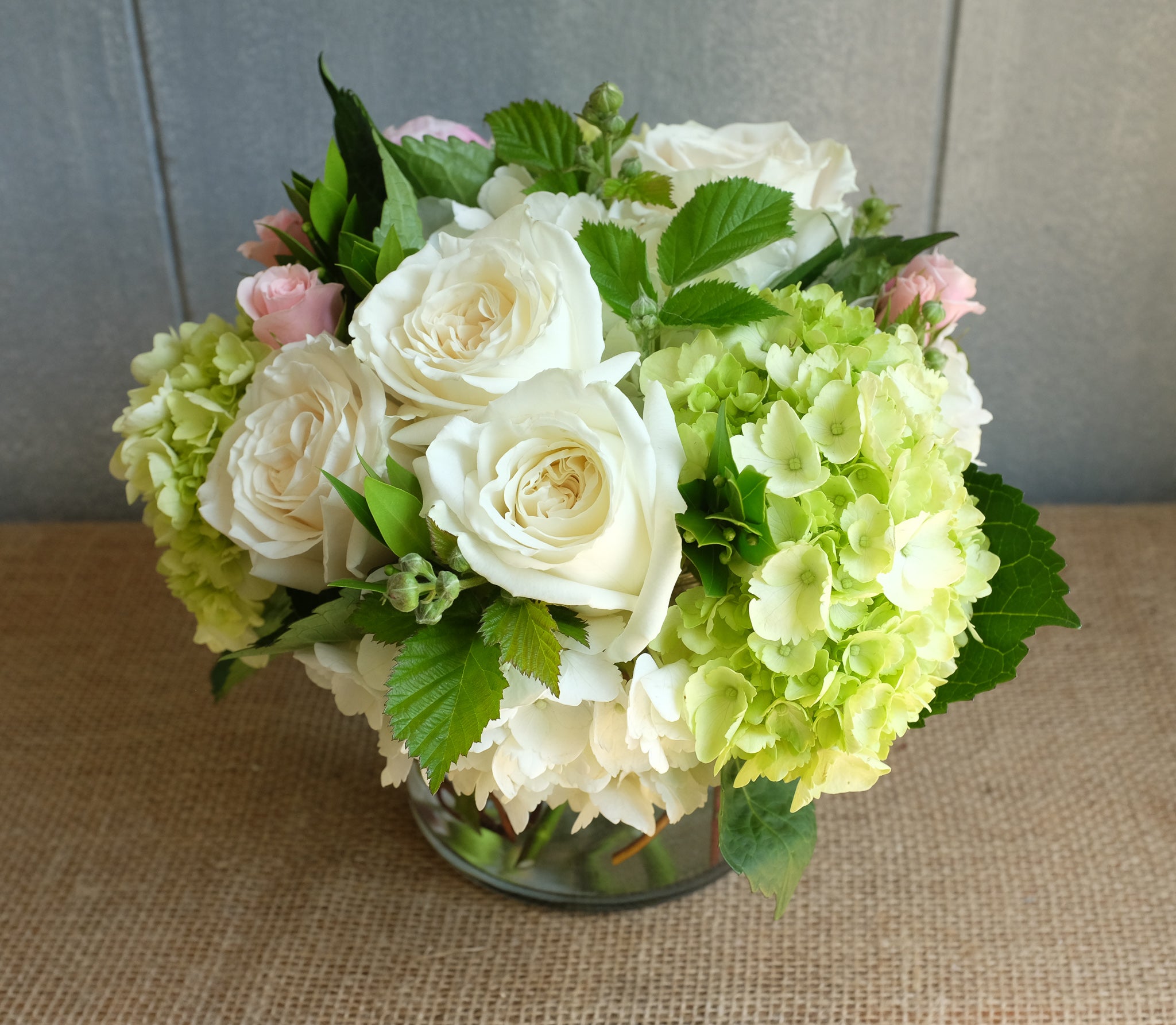 White and green bouquet of roses and hydrangea with a touch of pink.
