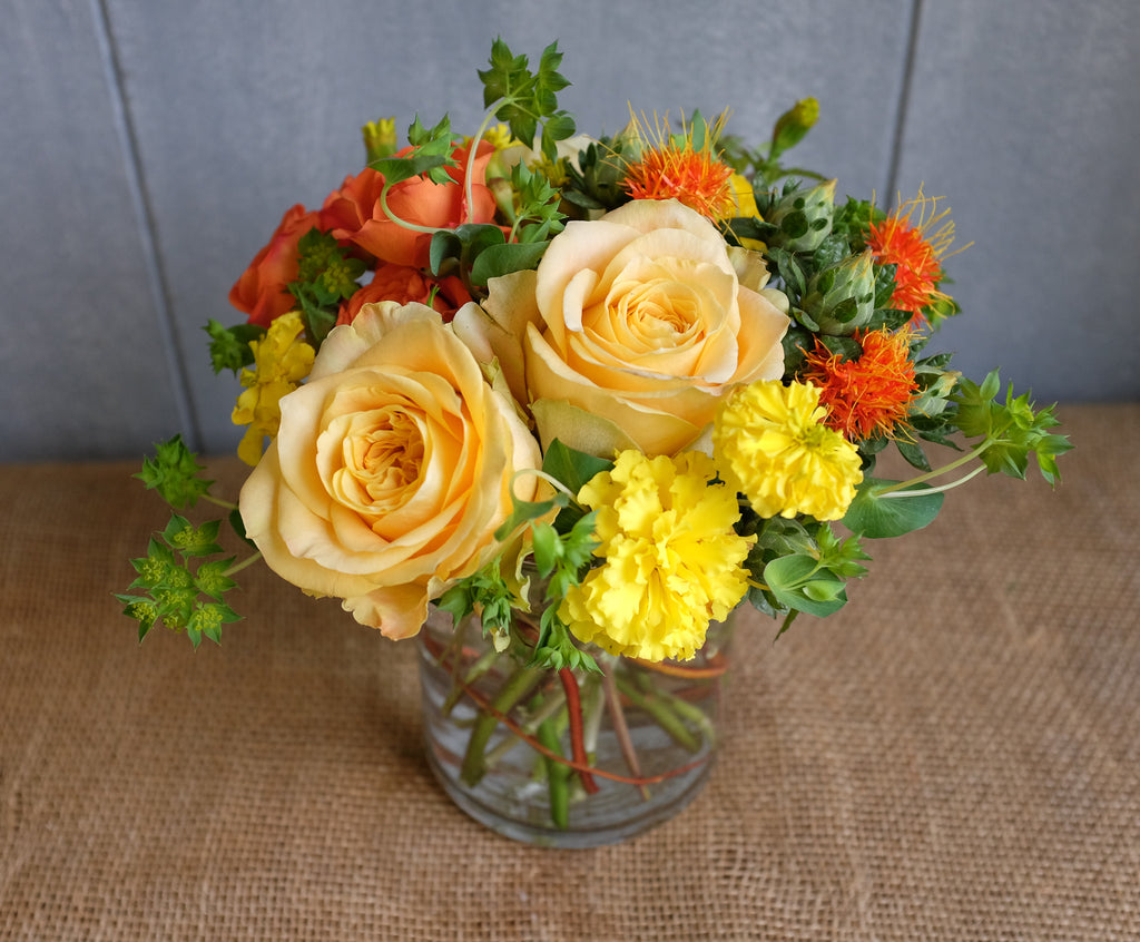 Bright floral bouquet with yellow roses and seasonal flowers in yellows and oranges