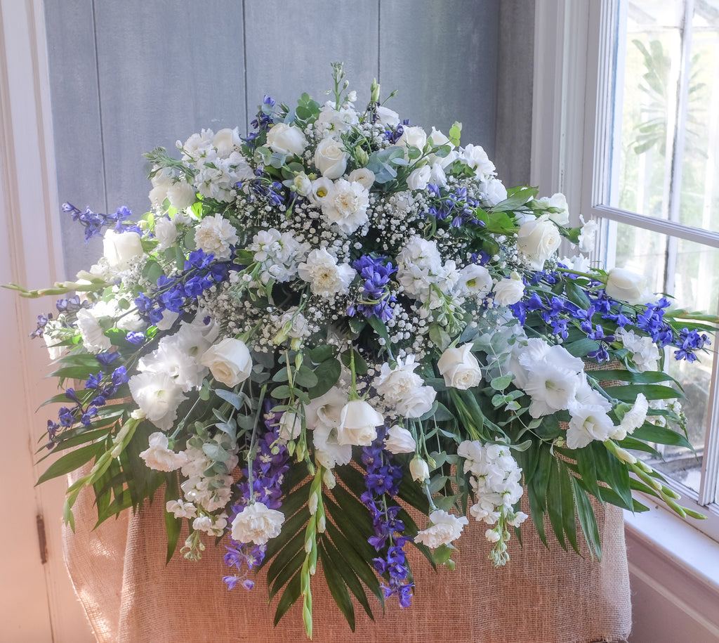 floral casket spray with roses, carnations, lisianthus, baby's breath, larkspur, and stock by Michler's Florist in Lexington, KY