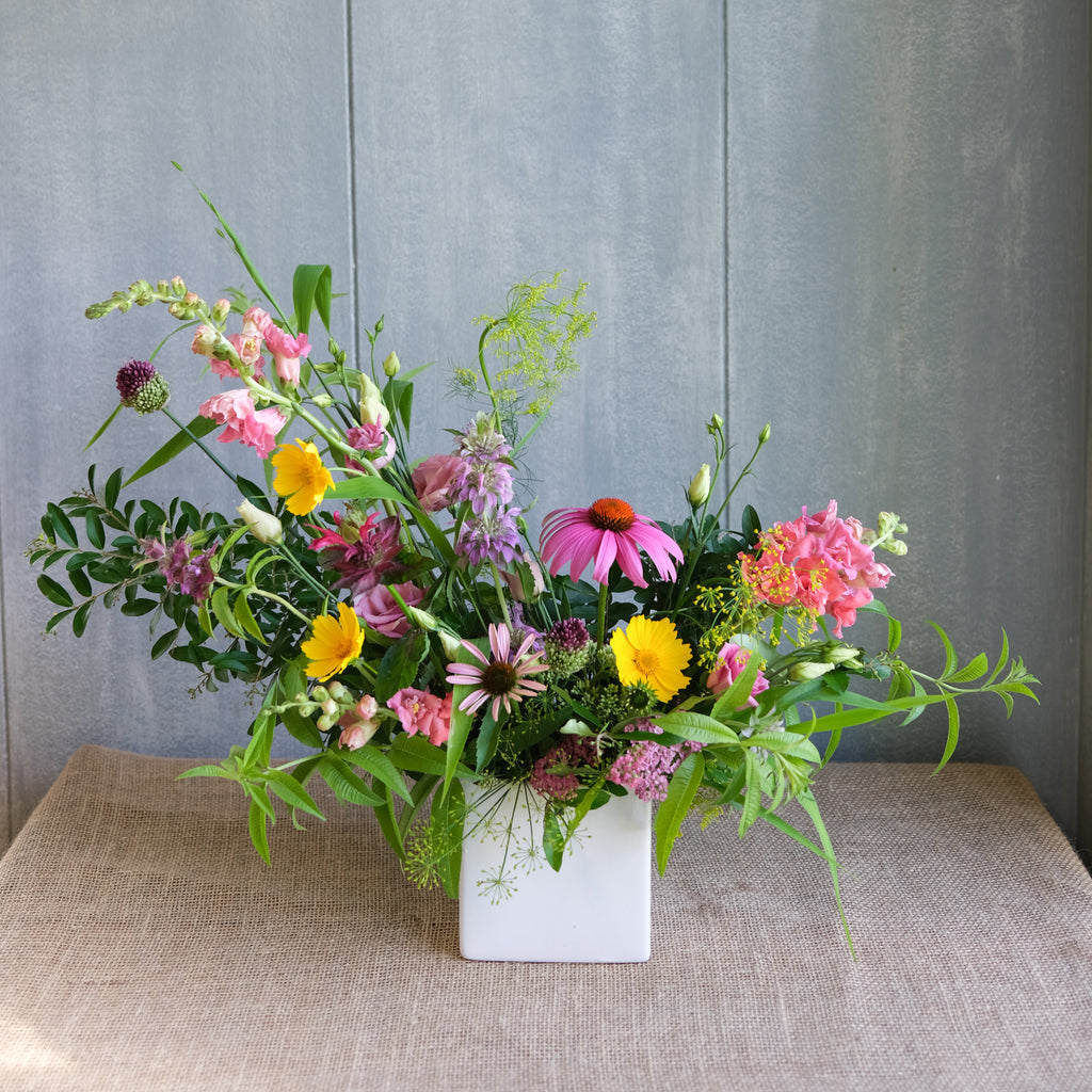 An asymmetrical, naturalistic flower arrangement made of colorful, seasonal flowers.