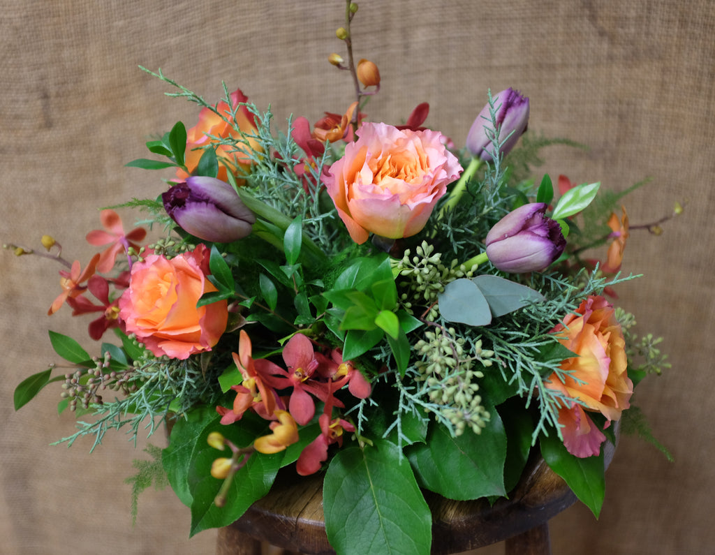 A round centerpiece in fall tones and mixed greenery