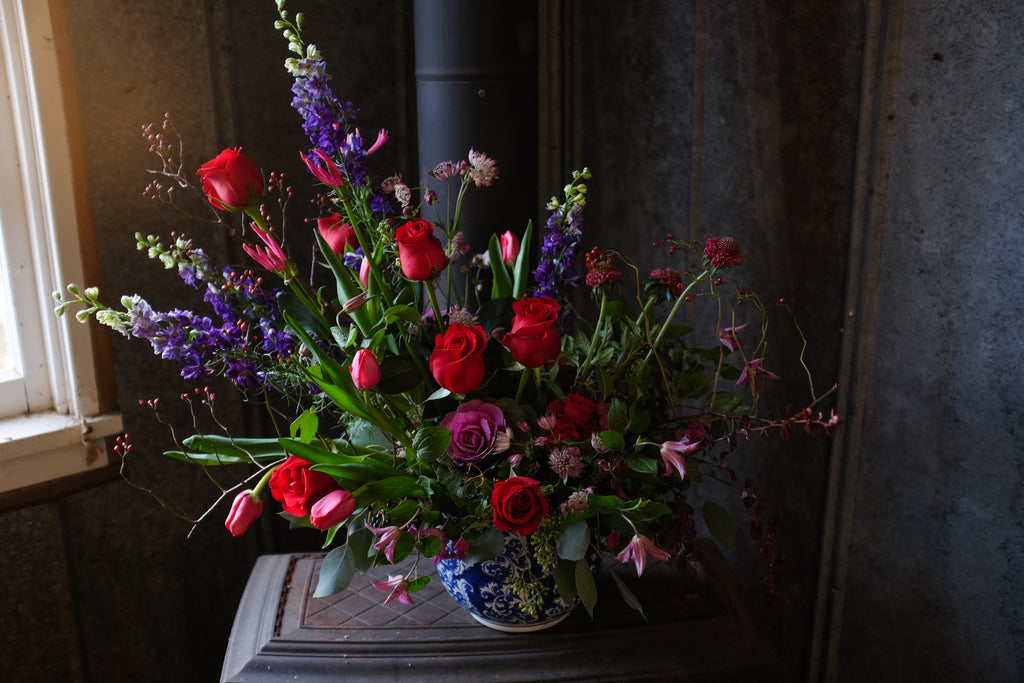prestige flower arrangement with red roses, blue delphinium, and greenery by Michler's