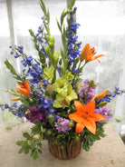 Funeral floral arrangement with orange lily, blue delphinium
