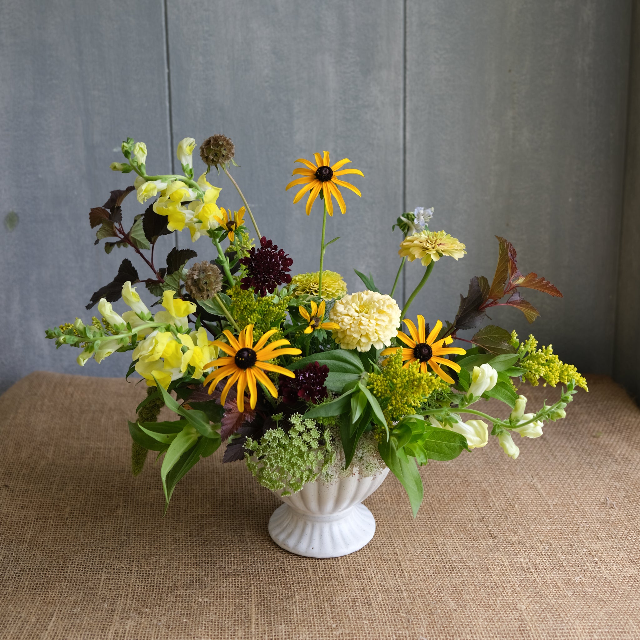 Asymmetrical, naturalistic arrangement featuring primarily yellow flowers