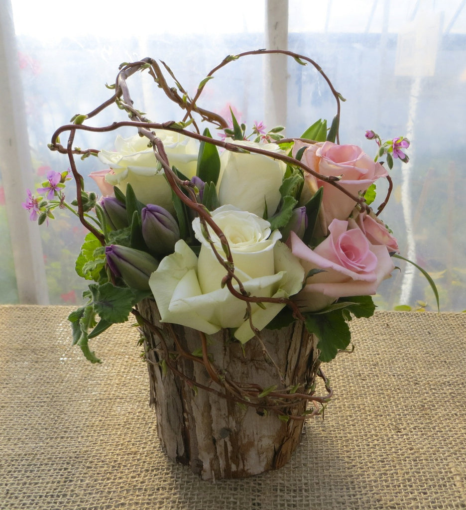 Rose arrangement in a bark pot with curly willow and tulips, designed by Michler's Florist in Lexington, KY